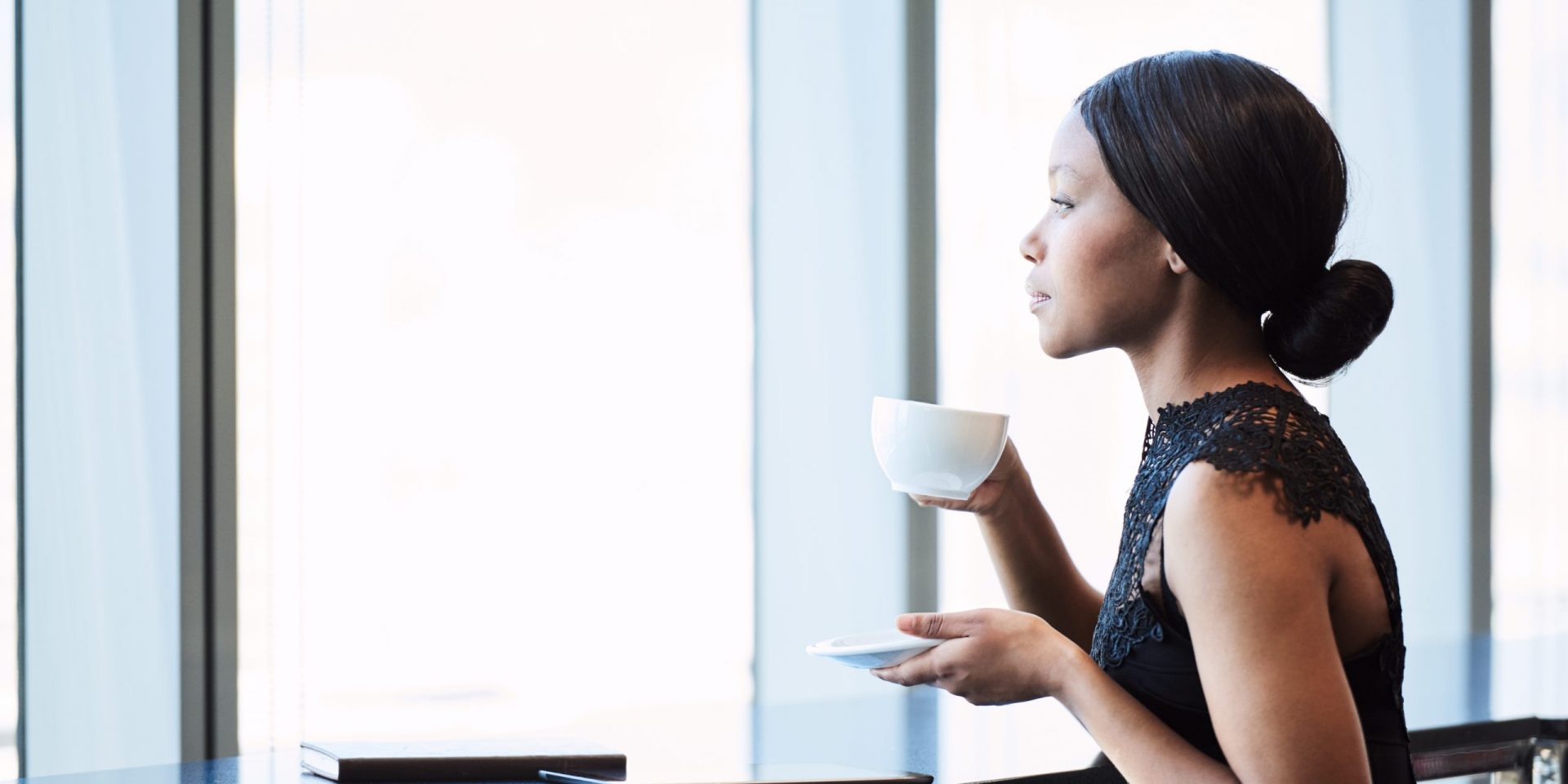 Woman with coffee and journal looking out of the window