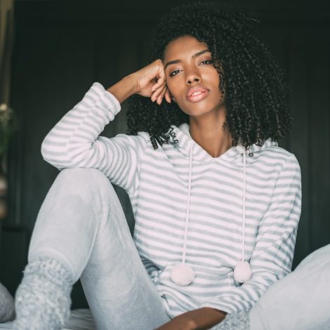 Beautiful thoughtful black woman sit on bed looking at the camera