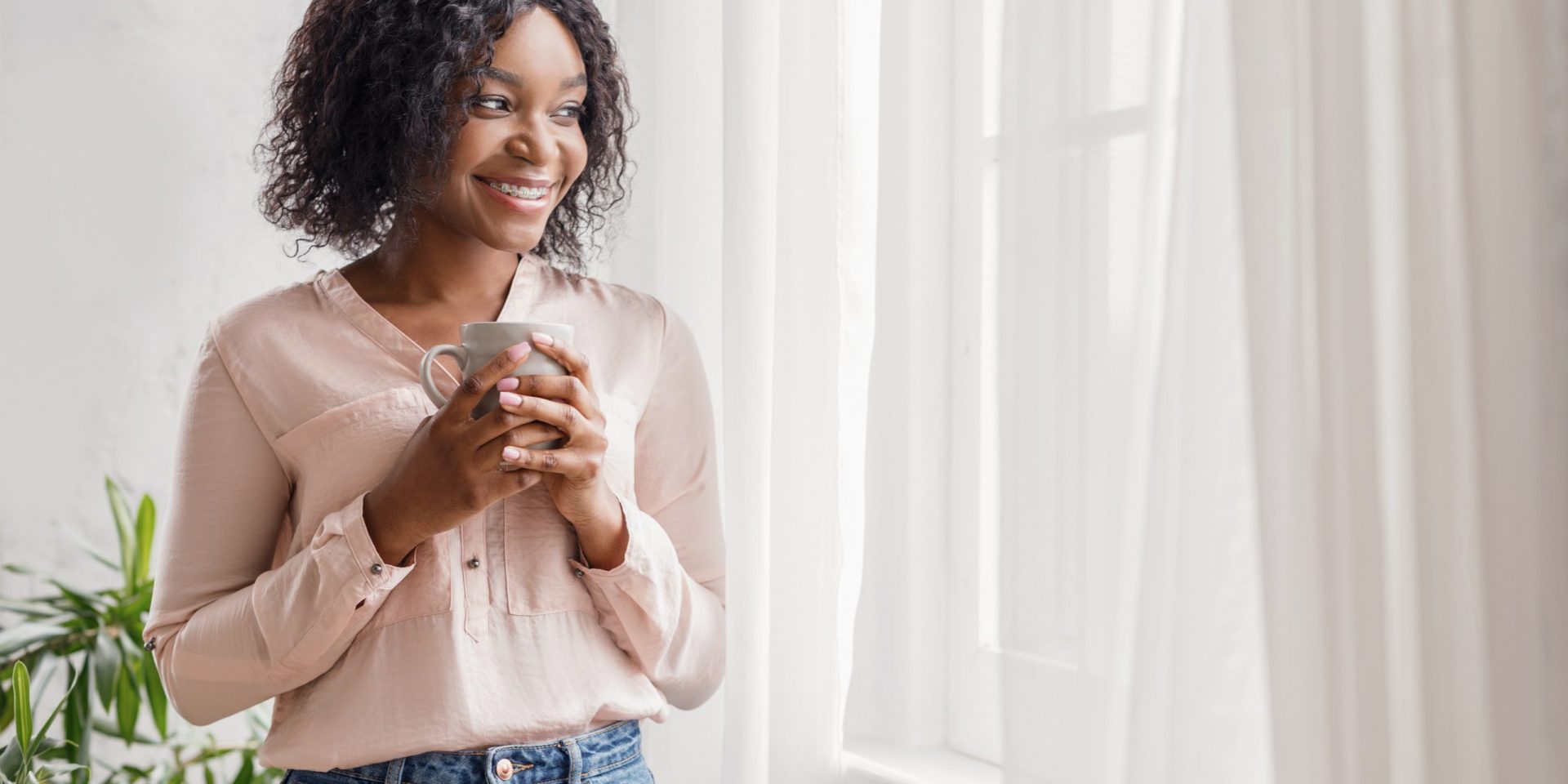 woman next to curtains drinking cofee