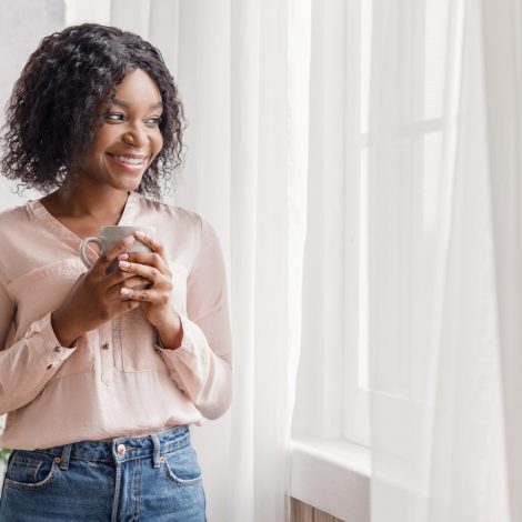 woman next to curtains drinking cofee