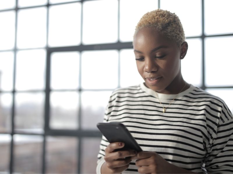 Woman in front of a window looking at her phone
