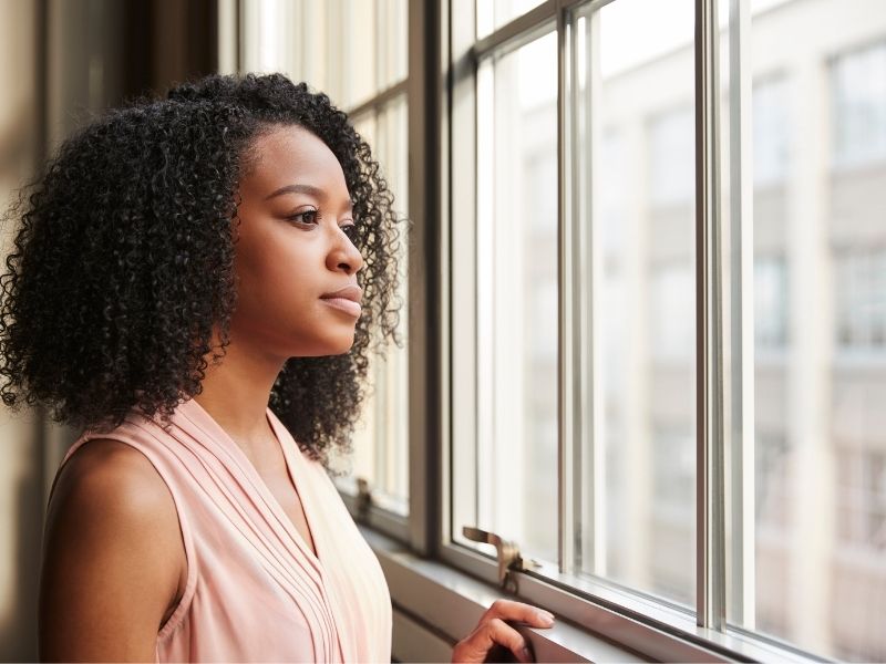Woman staring out of a building window