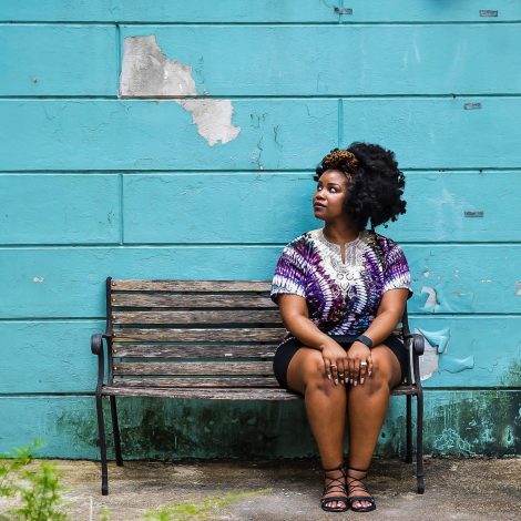 Woman sitting on bench in front of a blue wooden wall