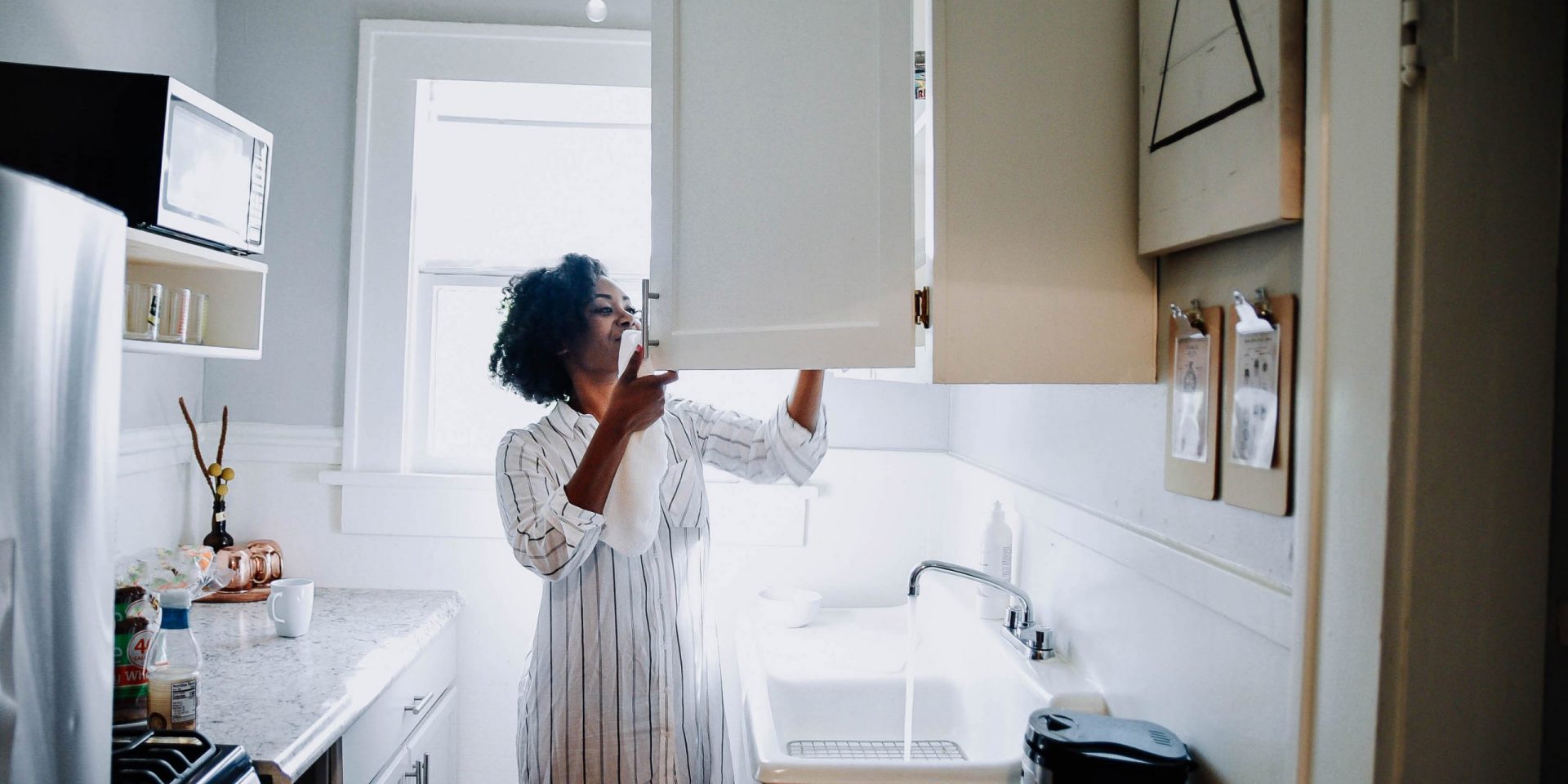Woman looking inside her kitchen cabinet