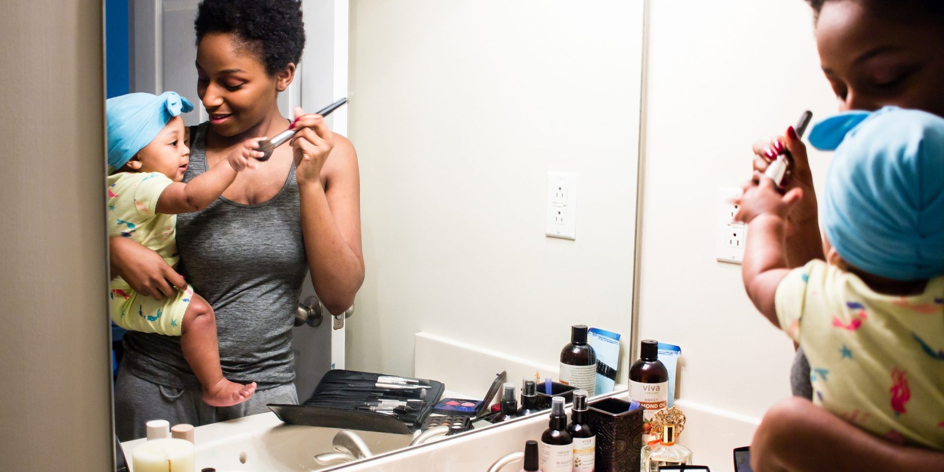 Woman and baby playing in front of bathroom sink