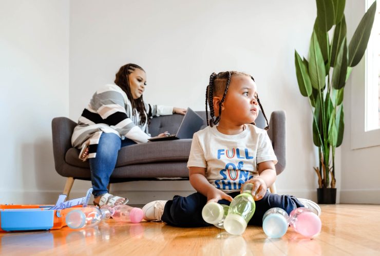 Woman on coach while baby plays with toys